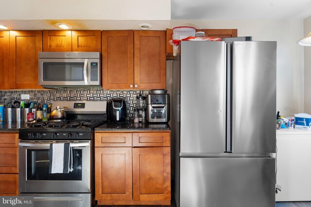102 W Walnut Park Dr, Philadelphia, PA 19120 - kitchen with stainless steel appliances, brown cabinets, dark stone countertops, and decorative backsplash
