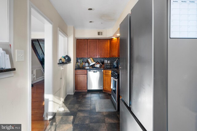 102 W Walnut Park Dr, Philadelphia, PA 19120 - kitchen with appliances with stainless steel finishes, backsplash, brown cabinets, dark countertops, and dark stone finish floors