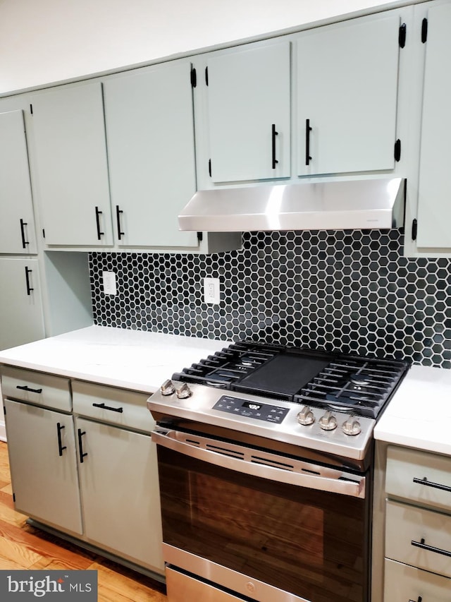 kitchen with decorative backsplash, light wood-type flooring, and stainless steel range with gas stovetop