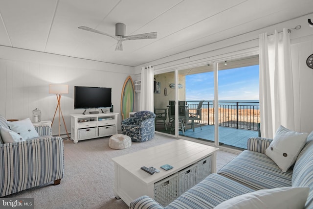 carpeted living room with ceiling fan and wooden walls