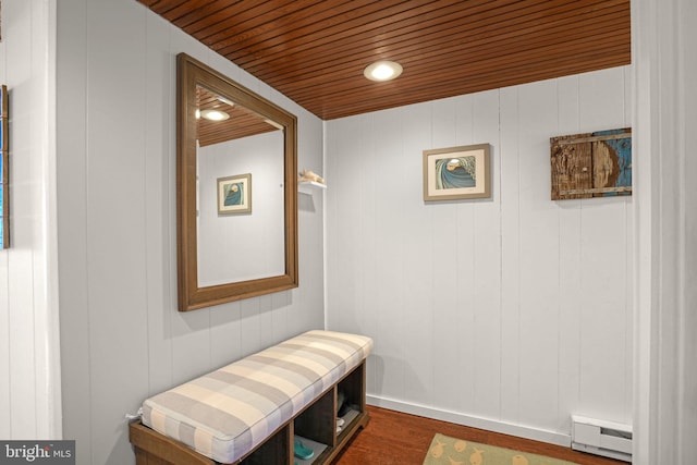 interior space featuring wood walls, wood ceiling, dark wood-type flooring, and a baseboard heating unit