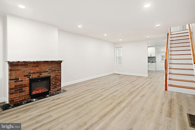 unfurnished living room featuring a fireplace and light hardwood / wood-style floors