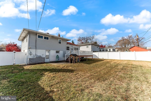 back of house featuring a lawn and a deck