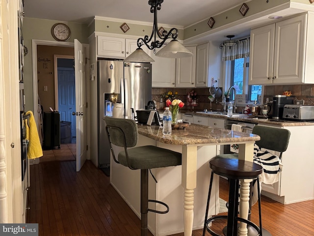 kitchen featuring decorative backsplash, a kitchen breakfast bar, wood-type flooring, pendant lighting, and white cabinets