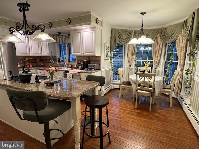 kitchen featuring dark wood-type flooring, white cabinetry, baseboard heating, and a notable chandelier