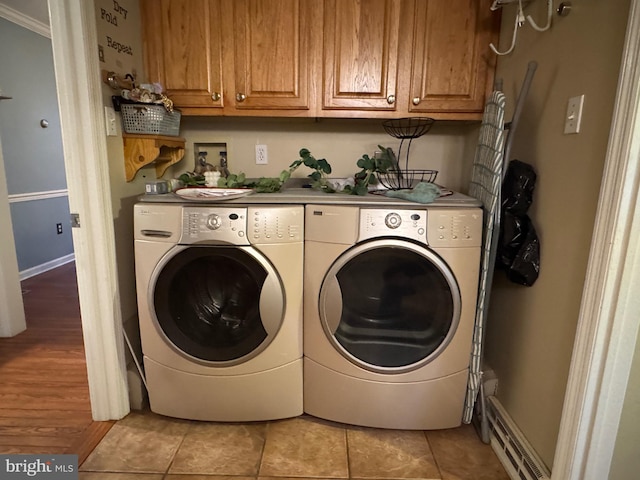 laundry area featuring cabinets, light hardwood / wood-style flooring, crown molding, and washing machine and clothes dryer