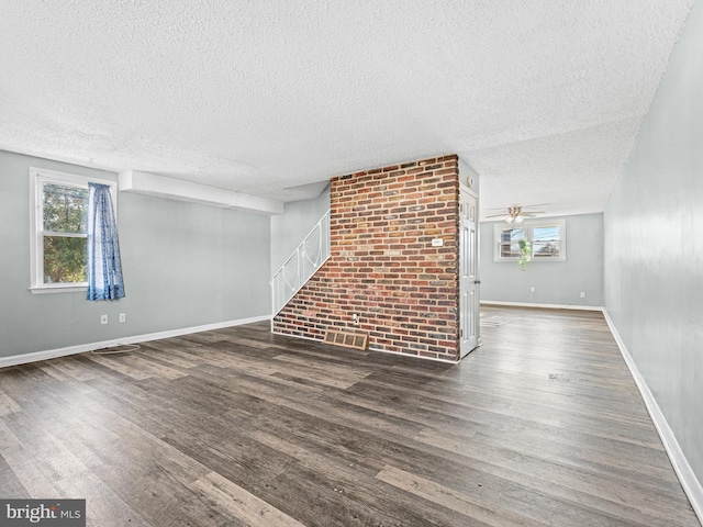 unfurnished living room with dark hardwood / wood-style flooring, a healthy amount of sunlight, and a textured ceiling