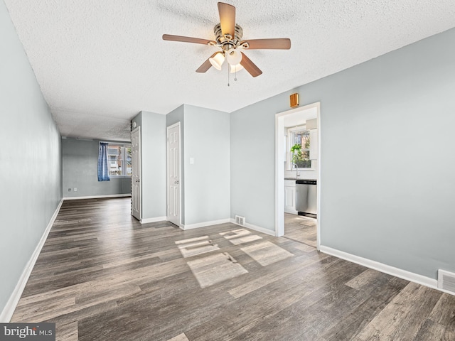 empty room with a textured ceiling, dark hardwood / wood-style flooring, ceiling fan, and a healthy amount of sunlight