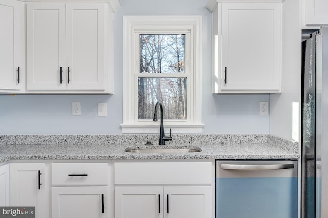 kitchen with white cabinets, stainless steel appliances, light stone counters, and sink