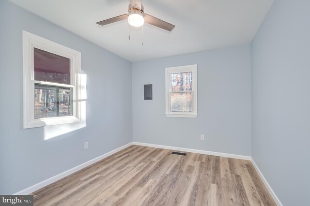 spare room with ceiling fan, electric panel, and light hardwood / wood-style flooring