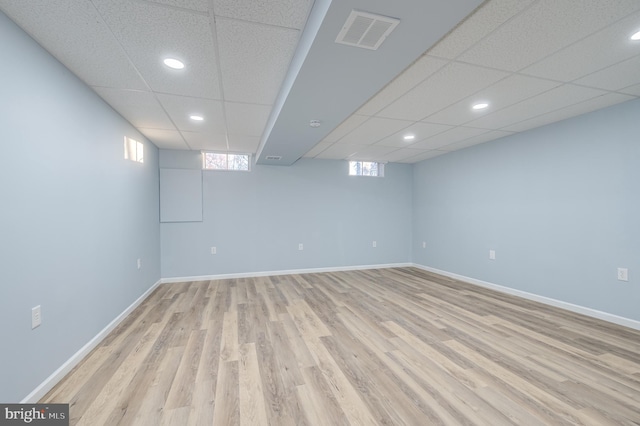 basement with a drop ceiling and light wood-type flooring