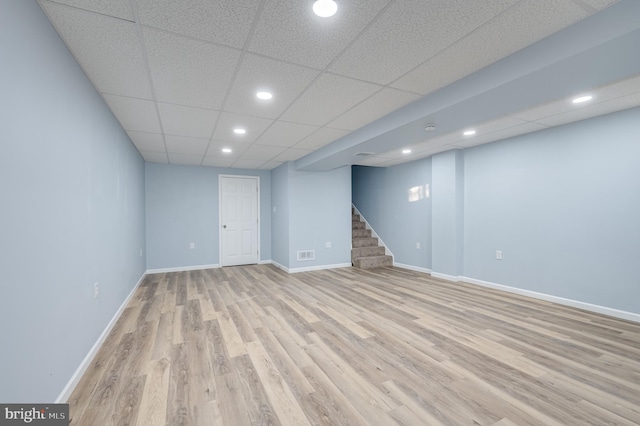 basement with a paneled ceiling and light hardwood / wood-style floors