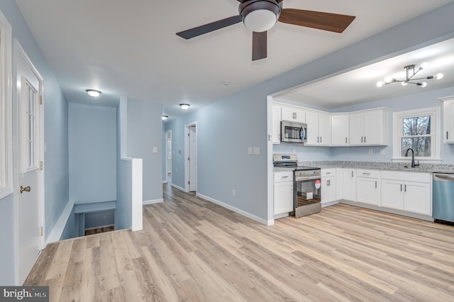 kitchen with white cabinets, light hardwood / wood-style flooring, ceiling fan, light stone countertops, and appliances with stainless steel finishes