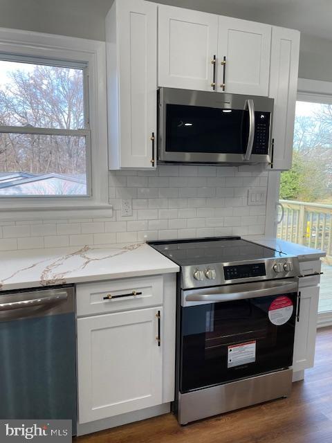 kitchen featuring light stone countertops, tasteful backsplash, stainless steel appliances, wood-type flooring, and white cabinets