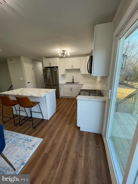 kitchen featuring dark wood-type flooring, white cabinets, sink, appliances with stainless steel finishes, and tasteful backsplash