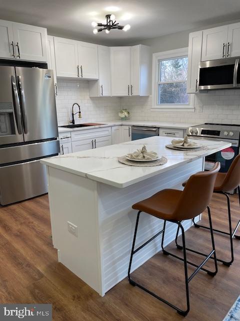 kitchen with a kitchen bar, appliances with stainless steel finishes, white cabinetry, and sink