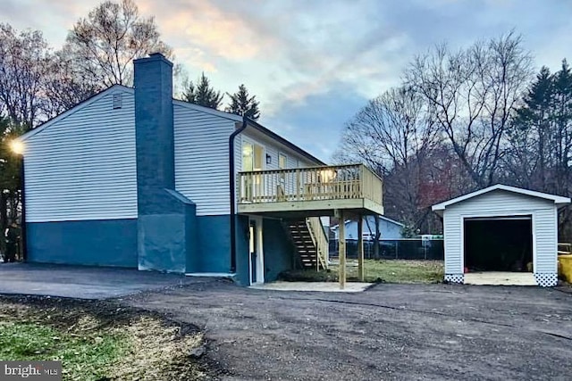 rear view of property featuring a deck, a garage, and an outdoor structure