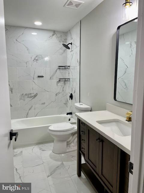 full bathroom featuring vanity, tiled shower / bath combo, and toilet