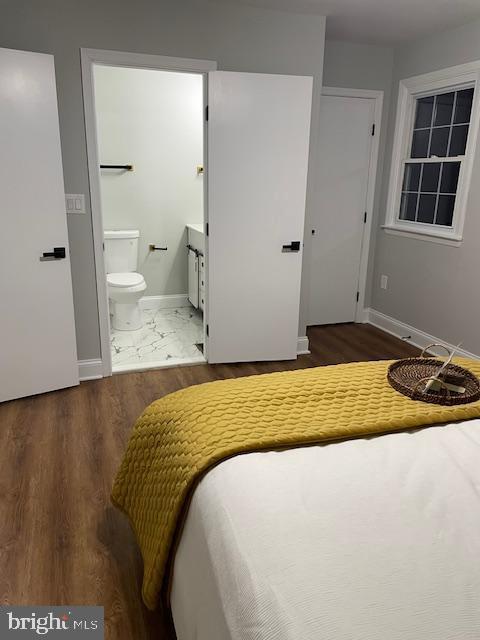 bedroom with ensuite bathroom and dark hardwood / wood-style flooring