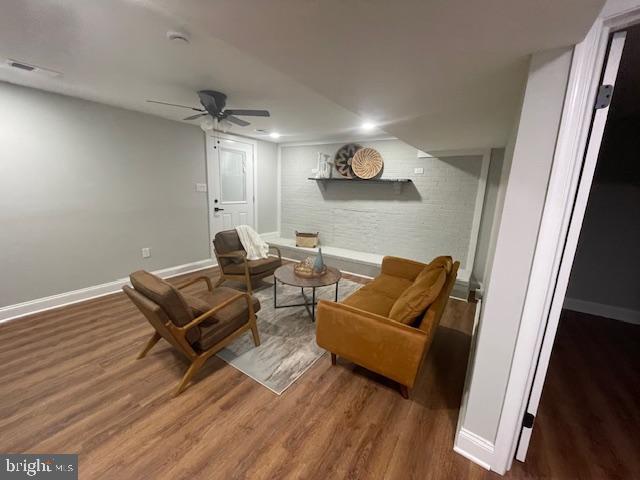 sitting room featuring ceiling fan, brick wall, and dark hardwood / wood-style floors