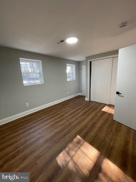 unfurnished bedroom with dark wood-type flooring and a closet