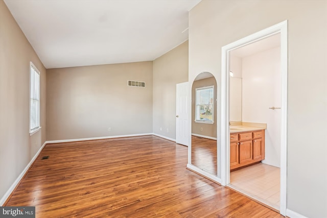 empty room with lofted ceiling and light hardwood / wood-style flooring