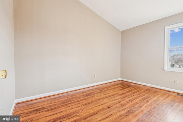 unfurnished room featuring lofted ceiling and light hardwood / wood-style floors