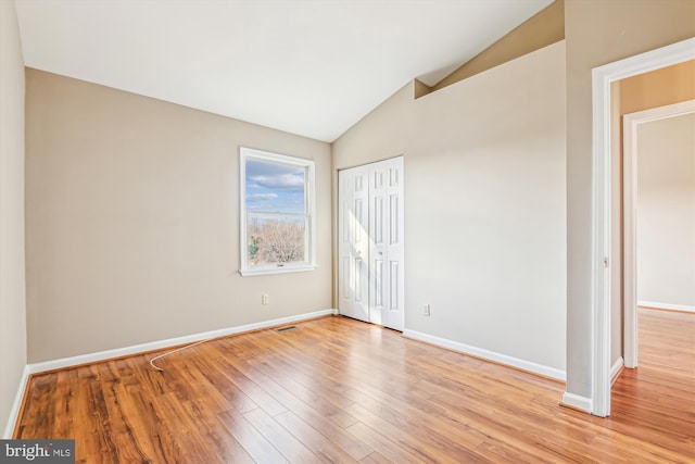 spare room with vaulted ceiling and light hardwood / wood-style flooring