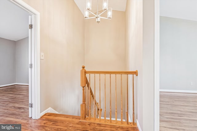 stairway featuring hardwood / wood-style flooring and a chandelier