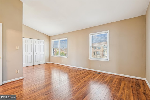 unfurnished bedroom featuring wood-type flooring, a closet, and vaulted ceiling