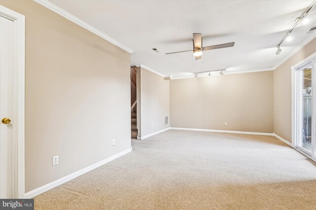 empty room featuring light carpet, crown molding, rail lighting, and ceiling fan