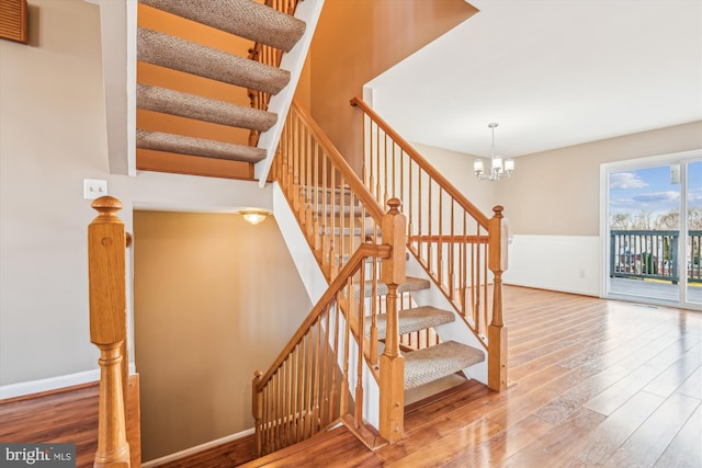 staircase featuring hardwood / wood-style floors and a chandelier