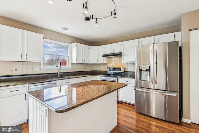 kitchen featuring stainless steel appliances, a center island, white cabinets, dark hardwood / wood-style flooring, and dark stone counters