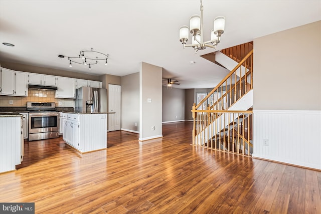 kitchen featuring pendant lighting, stainless steel appliances, light hardwood / wood-style floors, white cabinets, and decorative backsplash