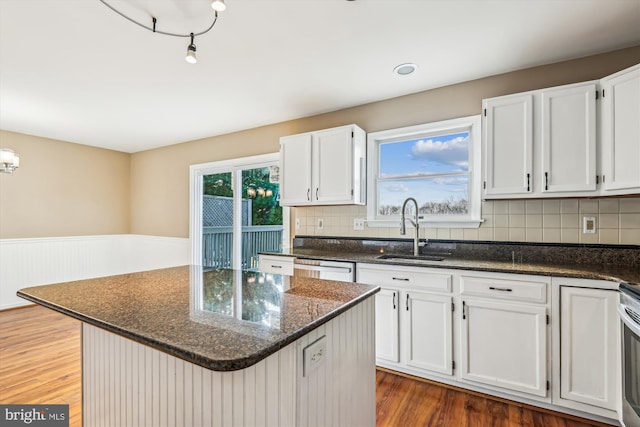 kitchen featuring a kitchen island, dark hardwood / wood-style floors, white cabinetry, sink, and dark stone countertops