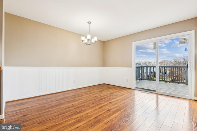 empty room with hardwood / wood-style flooring and a chandelier