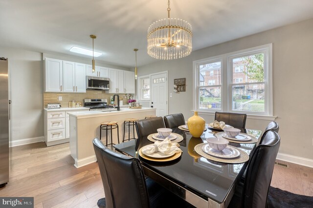 dining room featuring light hardwood / wood-style flooring, a notable chandelier, and sink