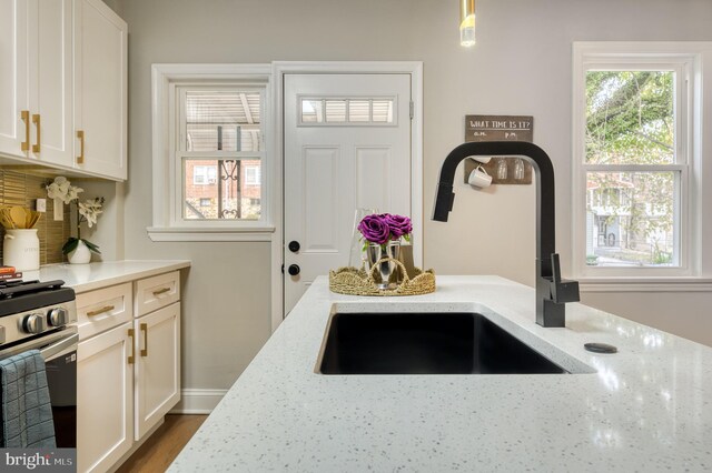 kitchen featuring white cabinetry, light stone countertops, stainless steel range, sink, and pendant lighting