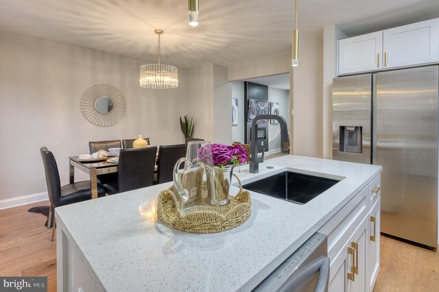 kitchen with light stone countertops, sink, light hardwood / wood-style flooring, white cabinets, and stainless steel fridge with ice dispenser