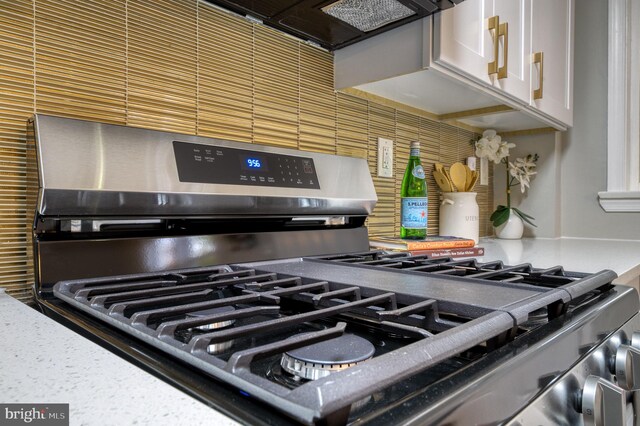 room details with premium range hood, white cabinetry, and stainless steel gas range oven