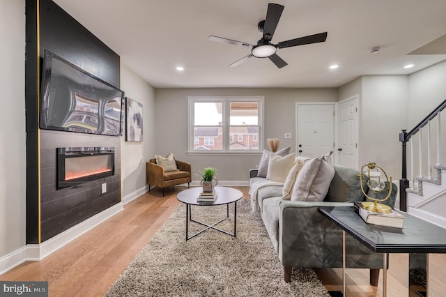 living room featuring ceiling fan, light hardwood / wood-style floors, and a fireplace