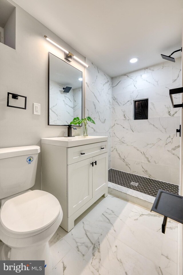 bathroom with tiled shower, vanity, and toilet