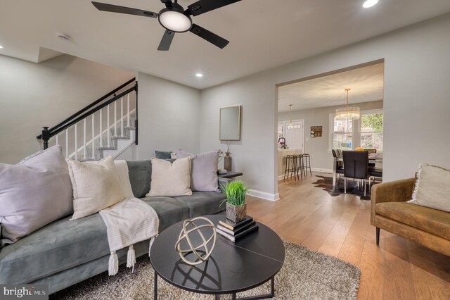 living room with hardwood / wood-style flooring and ceiling fan with notable chandelier