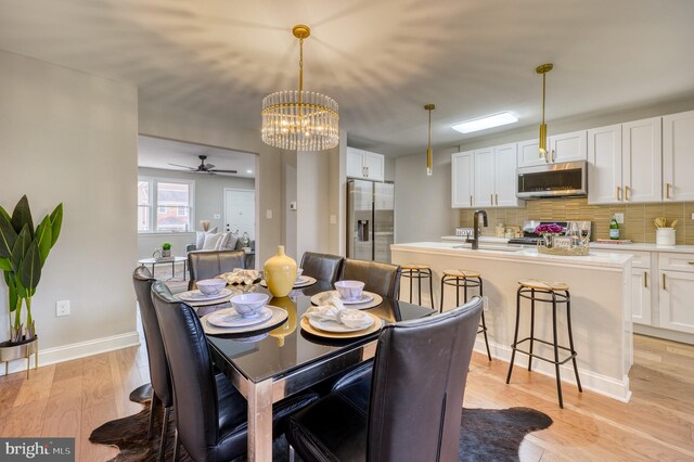 dining room with sink, ceiling fan with notable chandelier, and light wood-type flooring