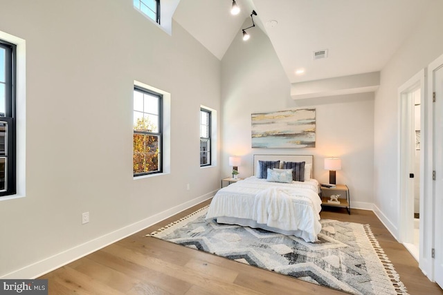 bedroom featuring high vaulted ceiling and hardwood / wood-style flooring