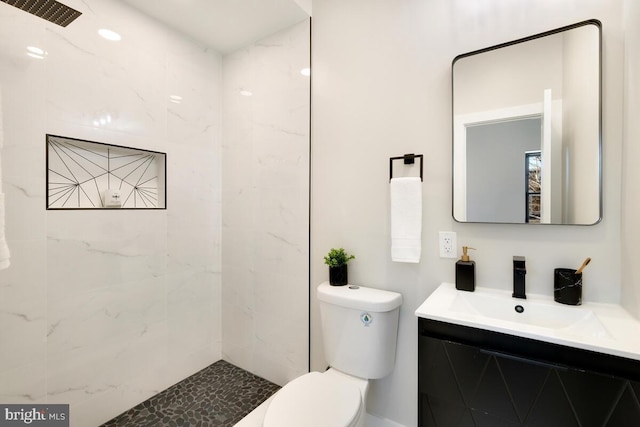 bathroom featuring vanity, toilet, and tiled shower