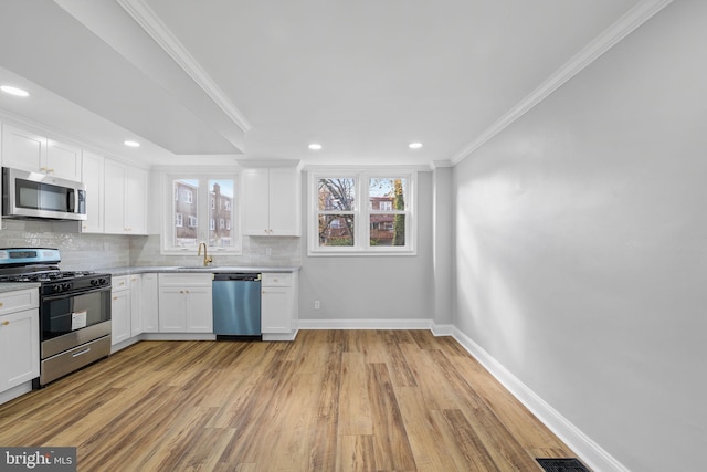 kitchen with white cabinets, light wood-type flooring, stainless steel appliances, and sink