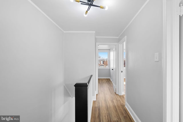 corridor featuring hardwood / wood-style floors, ornamental molding, and an inviting chandelier