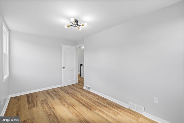 empty room with a chandelier and hardwood / wood-style floors