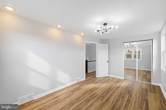 unfurnished bedroom with a chandelier, a closet, and wood-type flooring